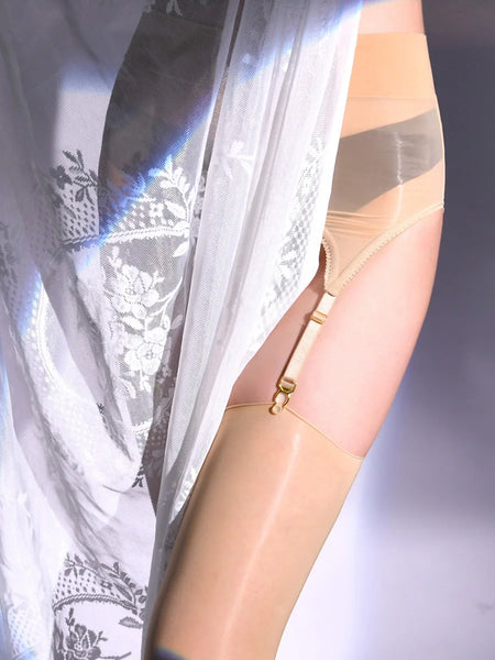 A woman posing in a beige glossy sheer thigh high stockings with matching glossy garter belt.