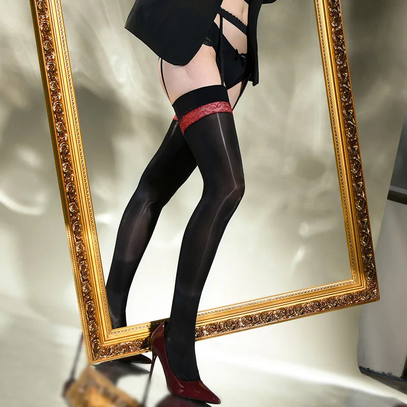 A woman posing in a black glossy thigh high stockings with red lace details, and attached garter straps with red high heels.