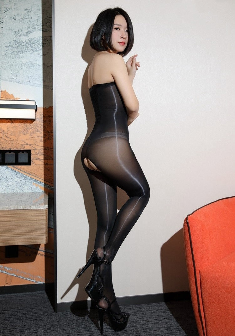 Woman posing in a black bodystocking with a tube top design, made of sheer, glossy material with crotchless feature.